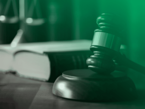 a imagem mostra uma mesa em um tribunal, com um exemplar da constituição e um malhete.