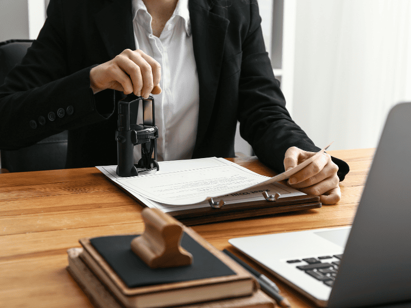 Mulher em um cartório autenticando e carimbando documentos.